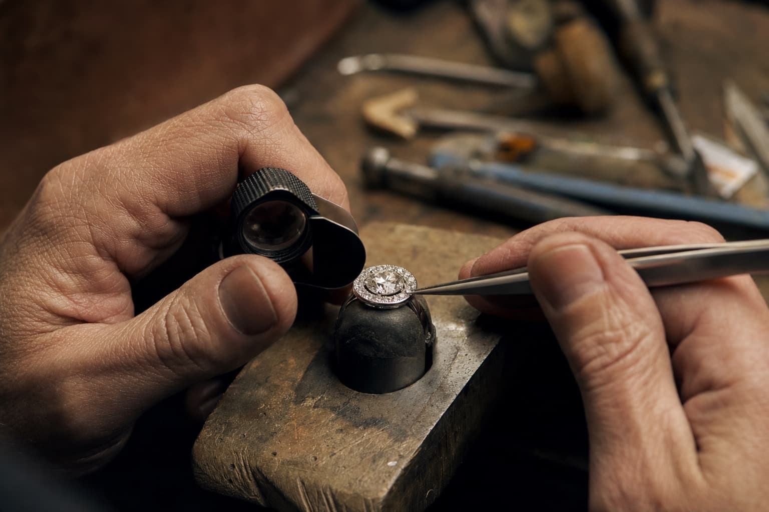 A jeweler setting a diamond by hand at the bench